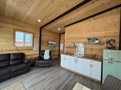 Finished timber interior with wood walls and ceiling, dark structural beams, living area, cabinetry, and retro-style refrigerator
