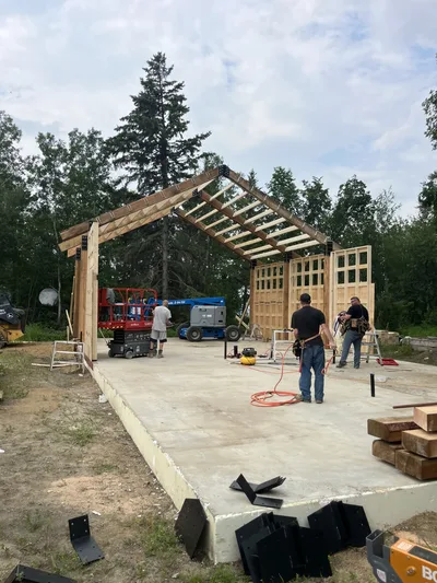 Construction crew working inside an open timber frame with exposed roof beams and framed walls