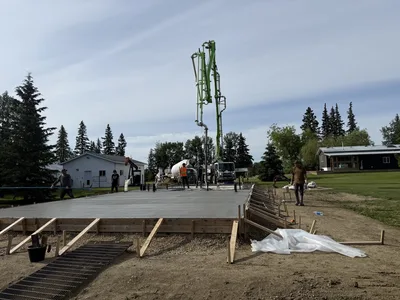 Concrete pump truck and crew working on a large slab foundation at a rural building site