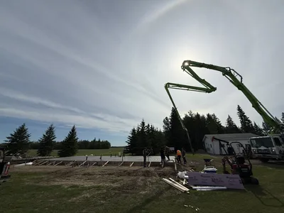 Crew placing and leveling concrete from a pump boom across a reinforced slab foundation