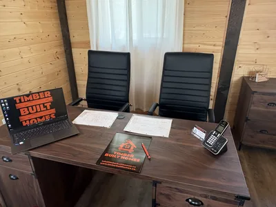 Timber Built Homes desk with plans, branded materials, laptop, and phone inside a timber-finished office