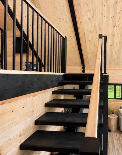 Open timber staircase with black treads and railings against natural wood walls and ceiling